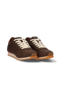 Zapatillas marrones con cordones crema, con un upper liso, paneles laterales texturizados y una suela de goma con un acento naranja contrastante.