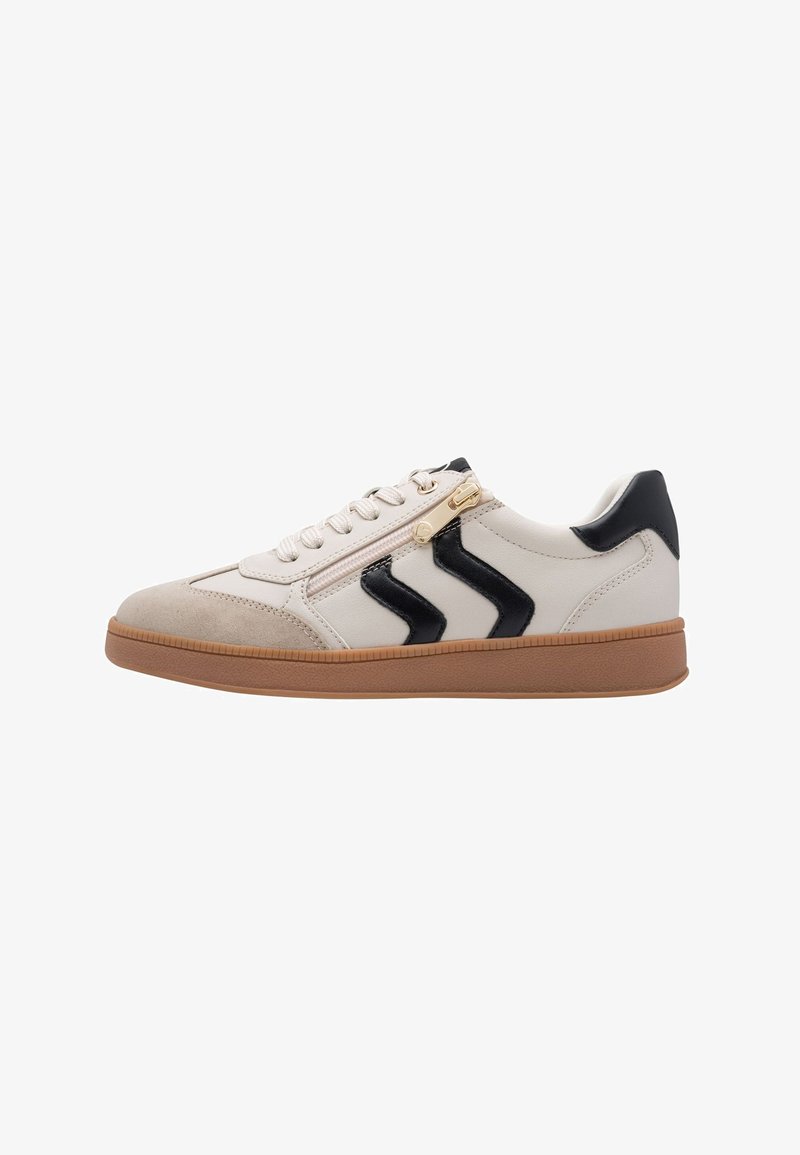 Basket blanche et beige avec semelle marron, bandes chevrons noires sur le côté, lacets à l'avant et détail de fermeture éclair près des lacets.