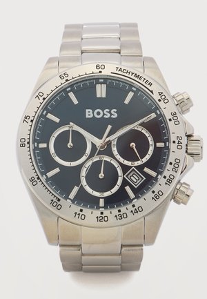 Silver metal wristwatch with black dial, three subdials, date display, tachymeter bezel, and BOSS logo at 12 o'clock.