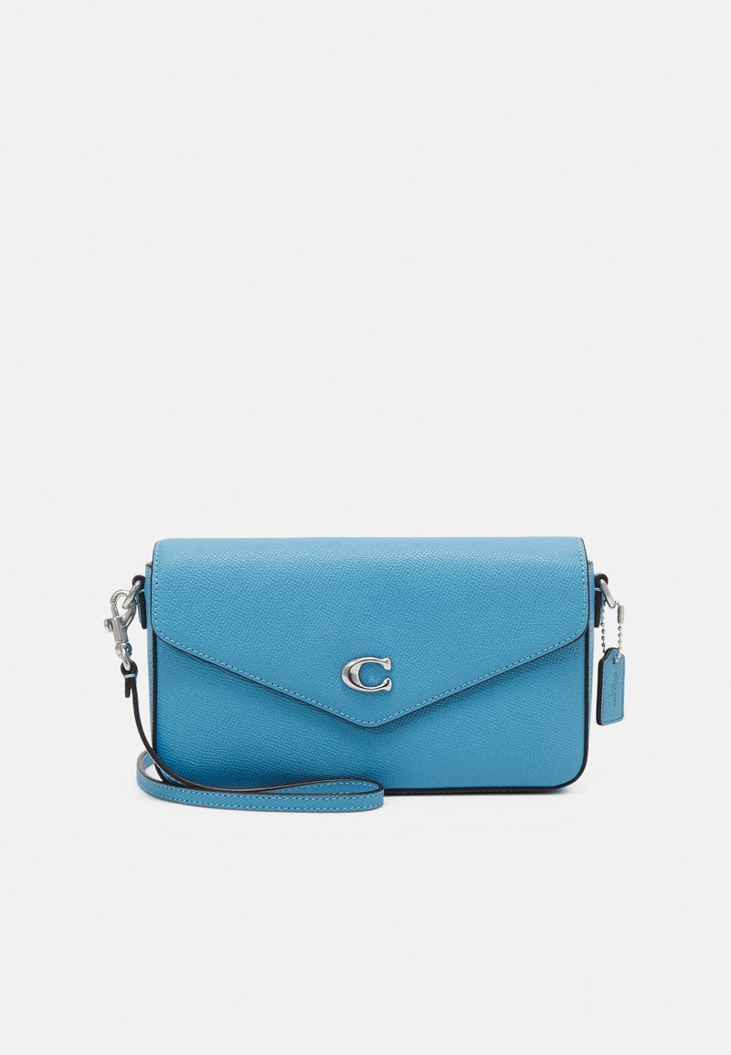 Blue leather crossbody bag with a triangular flap, featuring a silver logo, adjustable strap, and contrast stitching along the edges.