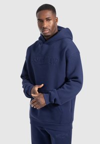 Felpa con cappuccio blu navy con logo testurizzato, cappuccio grande e tasca a marsupio. Realizzata in materiale morbido e resistente, presenta orli e polsini a coste.