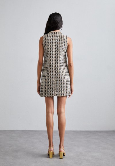 Ärmelloses Kleid aus texturiertem, gewebtem Stoff in Creme, Schwarz und Gold. Es hat ein figurbetontes Design und endet oberhalb des Knies.
