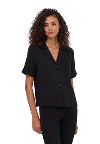 Camicia nera a maniche corte, in tessuto leggero, design con bottoni, polsini ripiegati, colletto piatto e orlo dritto, abbinata a pantaloni neri.