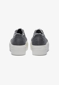 Graue Sneaker mit ausgefransten Kanten, denimähnlichem Stoff und einer dicken, strukturierten weißen Sohle. Die Rückansicht zeigt klare Linien und ein zurückhaltendes Design.