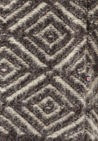 Braun- und cremefarbener Wollstoff mit erhabenem geometrischem Rautenmuster und kleinem Britisch-Flaggen-Tag auf der rechten Seite.