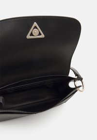Borsa a tracolla in pelle nera con un accento metallico triangolare, scomparti interni e una texture liscia. Presenta un dettaglio hardware circolare.