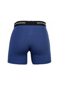 Blaue Boxershorts mit einem schwarzen Bündchen, auf dem das Logo "SCOTCH & SODA" prangt. Glatte Textur mit Nahtdetails entlang der Kanten.