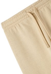 Beżowe dresy bawełniane z elastycznym pasem. Posiadają sznurek i gładką fakturę. Prosty design bez wzorów czy akcentów.