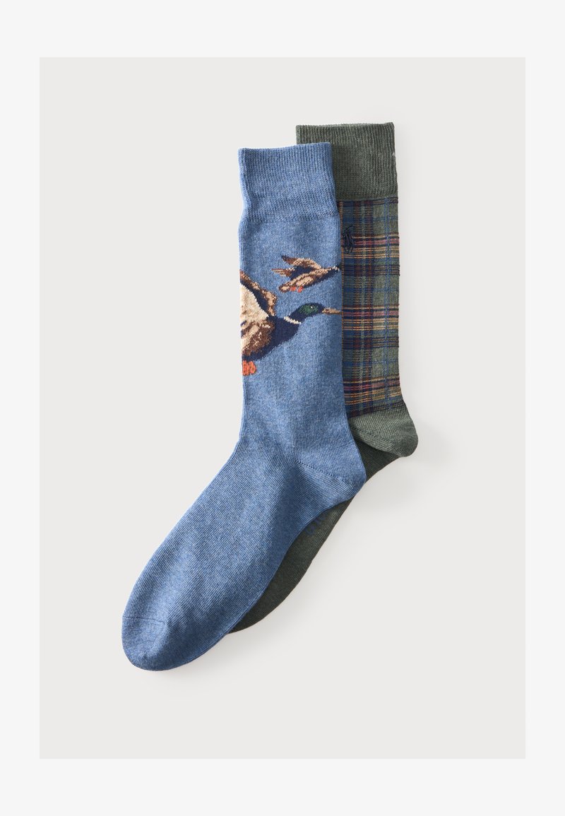 Deux paires de chaussettes, une bleue avec des motifs de canards volants, une vert olive avec un motif à carreaux, posées en chevauchement sur un fond uni.