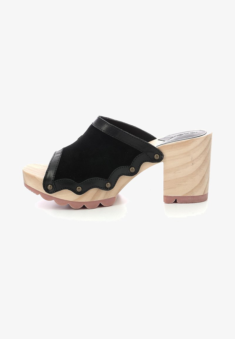 Le zoccoli in camoscio nero presentano una punta arrotondata, un bordo scallopato, borchie in ottone e un tacco in legno chiaro con fondo testurizzato.