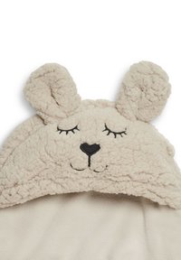 Beige plush blanket with a hood featuring bunny ears, embroidered face details, and soft fleece texture throughout.
