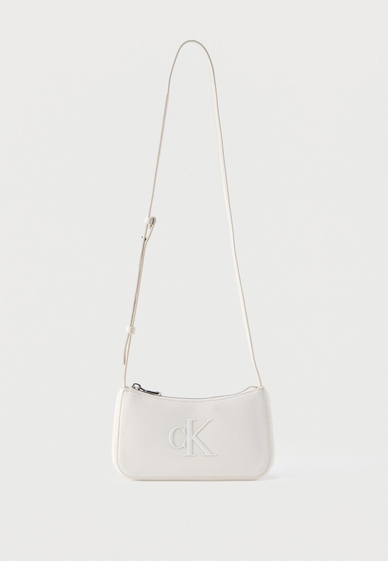 Κρεμ χρωματισμένη δερμάτινη τσάντα ώμου με ρυθμιζόμενο λουρί και ανάγλυφο λογότυπο "cK" στο μπροστινό μέρος, κλείσιμο με φερμουάρ.