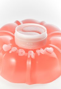Patch oculaire rétinien PDRN dans un pot blanc au design gélatineux texturé, posé sur une base en caoutchouc ronde rose avec des accents de cœur et de lettres.