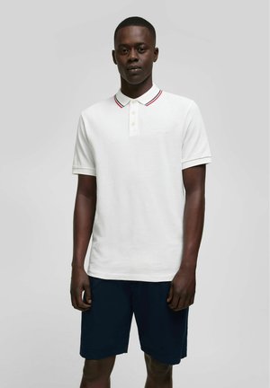 Witte polo shirt met een drieknoopsluiting, voorzien van rood en marineblauwe gestreepte kraagaccenten, gecombineerd met marineblauwe shorts. Glad katoenweefsel.