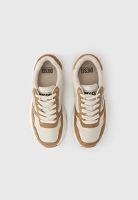 Μπεζ και καφέ αθλητικά παπούτσια με σουέντ και λείο ύφασμα. Διαθέτουν κορδόνια, στρογγυλεμένο μπροστινό μέρος και χαμηλό προφίλ. Λογότυπο στην γλώσσα του παπουτσιού.