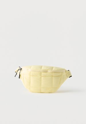 Hellgelbe gesteppte Bauchtasche mit Reißverschluss oben und verstellbarem Riemen vor weißem Hintergrund.
