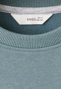 Světlomodrý žebrovaný límec svetr s bílou etiketou s názvem značky MNG, velikost 2-3, výška 98 cm.