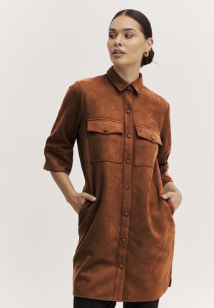 Rostfarbendes, knöpfbares Hemdkleid mit zwei Brusttaschen, einem Kragen und 3/4-Ärmeln, aus einem weichen, strukturierten Material hergestellt.