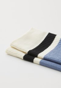 Knitted socks featuring a ribbed texture in cream, black, and light blue with horizontal stripes. Soft, breathable fabric.