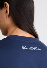 Marineblå bomulds T-shirt med rund halsudskæring og rygbroderi, der står "Vivere Per Sempre" i hvid tekst.