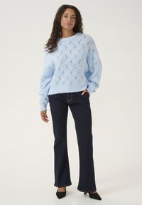 Hele sinine kudumine särk avatud muster, pikad varrukad ja soonikäär, kombineeritud tume flared teksade ja mustade teravaotsaga kingadega.