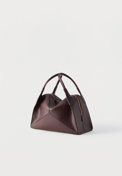 Bolso de piel marrón oscuro con dos asas y una cremallera dorada, con un diseño geométrico plegado sobre un fondo claro y liso.