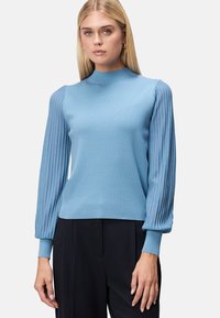 Jasnoniebieski sweter z dopasowanym fasonem i rękawami w balonowym stylu z prążkowanym wykończeniem. Gładka faktura, wysoki dekolt i kontrastowy design rękawów.