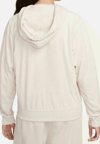 Ljusbeige hoodie med lång ärm, mjuk textur, ribbad mudd och avslappnad passform. Synlig sömnad längs huvan och fållen.