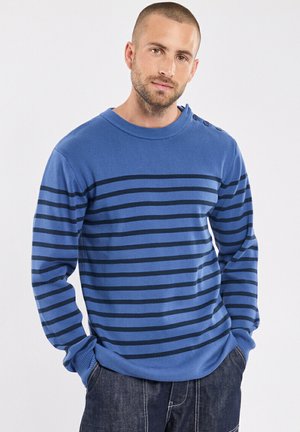 Pull à manches longues bleu avec des rayures horizontales marine, col rond à côtes et accents de boutons sur les épaules ; tissu tricoté texturé.