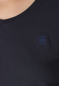 Σκοτεινό ναυτικό μπλουζάκι από βαμβάκι με ριγωτό λαιμό και μικρό κεντητό λογότυπο στην επάνω αριστερή πλευρά. Λείο υλικό, εφαρμοστή σχεδίαση.