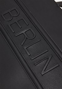 Sac en cuir noir au toucher texturé avec un motif en relief "BERLIN" au centre. Bords lisses et coutures contrastées.