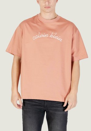 T-shirt oversize rosa chiaro in cotone, con logo "calvin klein" ricamato in bianco sul petto. Maniche corte, scollo rotondo.