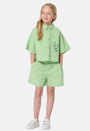 Chemise en coton vert clair à manches courtes avec une poche et le logo KENZO ; short assorti ; baskets blanches. Texture lisse, coupe décontractée.