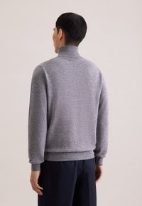 Grauer Strickpullover mit hohem Kragen und gerippten Bündchen. Verfügt über eine lockere Passform und eine weiche Textur. Einfaches, klar strukturiertes Design ohne Muster.