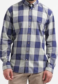 Camicia con bottoni caratterizzata da ampi quadretti blu navy e grigio chiaro, realizzata in tessuto morbido, con colletto e un piccolo logo sul petto.