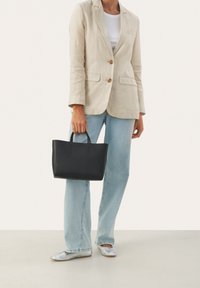 Musta nahkainen kassi lyhyillä kahvoilla, jämäkkä muoto, sileä pinta ja minimalistinen muotoilu. Yhdistettynä vaalean liinablazerin ja farkkujen kanssa.