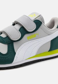Baskets vertes et grises avec des straps velcro, accents blancs et logo PUMA. Comprend du cuir et du daim avec un design texturé.