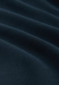 Sötétkék szövet, sima, texturált felülettel, egyenletesen elhelyezkedő, feltűnő redőkkel. Az anyag puhanak és enyhén tükröződőnek tűnik.