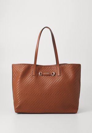 Bruine geweven leren tote bag met twee hengsels en een metalen Guess-logoplaatje aan de voorkant in het midden.