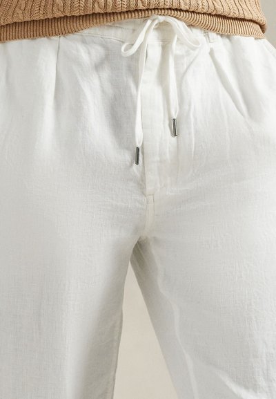 Λινά λευκά παντελόνια με άνετη εφαρμογή, διαθέτουν ζωνάκι με κορδόνι στη μέση και ασημένιες μεταλλικές λεπτομέρειες. Ομαλή υφή, ελαφρύ ύφασμα.