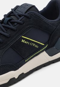 Námořnické tenisky s kombinací semišových a síťovinových materiálů. Výrazné zelené akcenty, polstrovaný límec a texturovaná gumová podrážka.