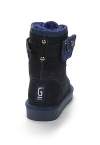 Bota corta azul marino hecha de material de ante con un forro suave, detalles de botones y un parche de la marca, que cuenta con una suela de goma.