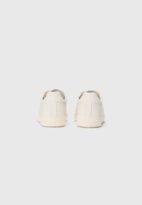 Pair of clean white low-top sneakers shown from the back on a plain white background.