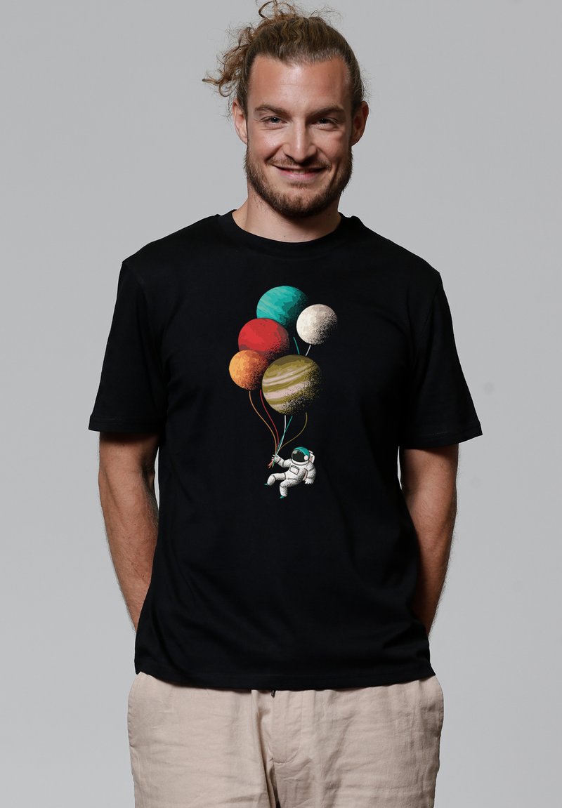 Zwarte T-shirt met een kleurrafische afbeelding van een astronaut die ballonnen vasthoudt, geïllustreerd als planeten. Korte mouwen en ronde halslijn.