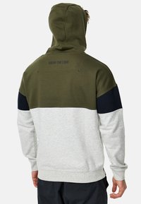Grøn og grå farveblokeret hoodie med snoretr�æk, der har marineblå detaljer. "WEAR THE CODE" tekst på bagsiden. Blødt stof.