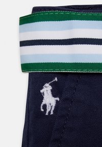 Marinblå tygshorts med en vit broderad polo-spelare logotyp; midjebandet har gröna, marinblå och ljusblå horisontella ränder.