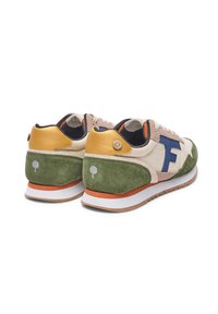 Les baskets présentent un corps en daim beige avec des accents verts, un talon en cuir doré et un logo bleu. Des détails notables incluent un emblème d'arbre et des lacets orange.