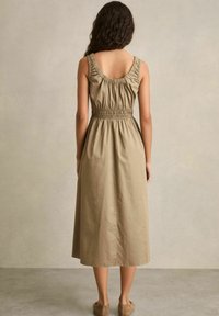 Khaki midi-jurk met een getailleerde taille, ronde achterkant en geraffineerde details bij de schouders. Glad materiaal en een ontspannen silhouet.