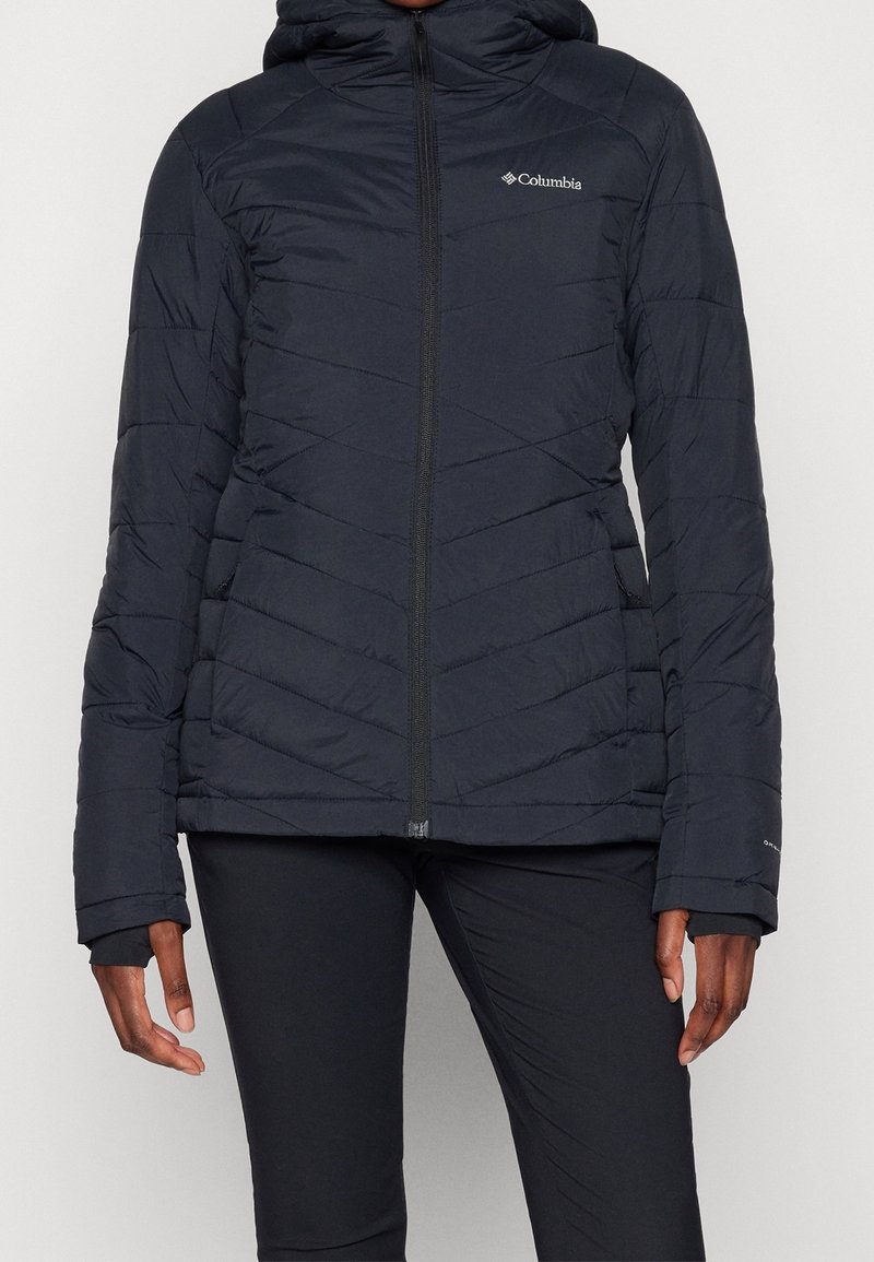 Giacca a vento in navy scuro, con cappuccio, design a motivo diagonale, zip frontale e dettaglio del logo sul petto.