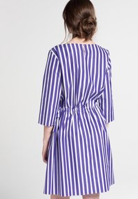 Fialové a bílé pruhované šaty s tříčtvrtečními rukávy, elastickým pasem a knoflíkovým uzávěrem na zádech. Hladká textury látky.